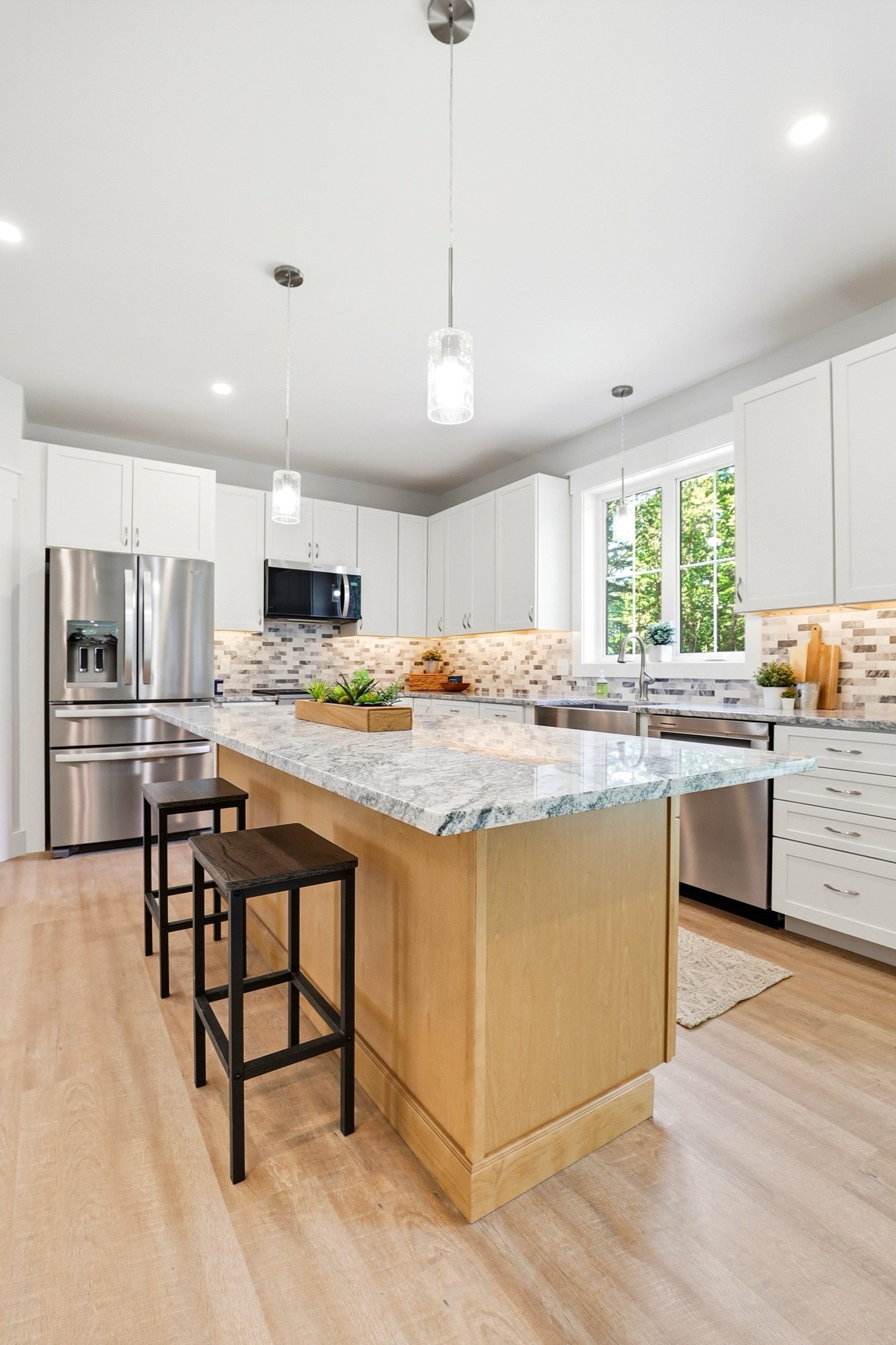 Bright white kitchen with granite island and stainless appliances