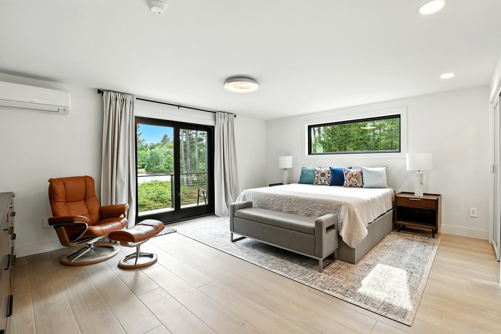 Primary bedroom with sliding doors to a wooded waterfront view