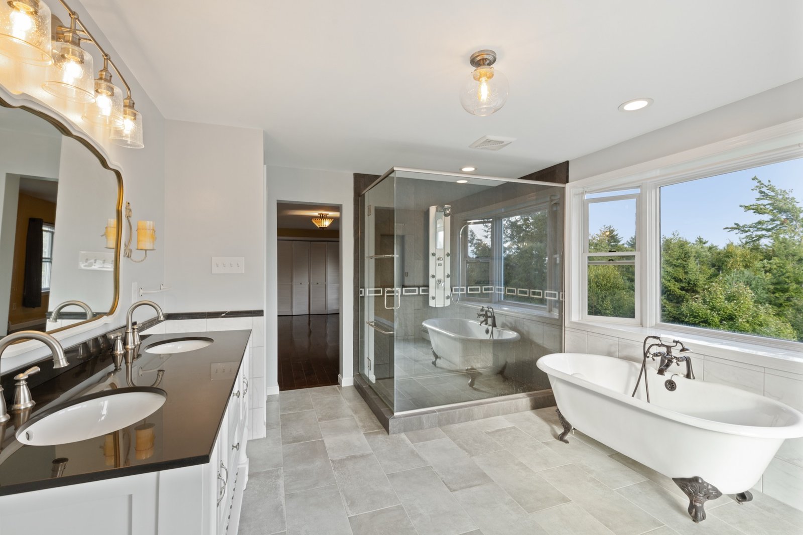 Primary bath with double vanity, glass shower, and clawfoot tub