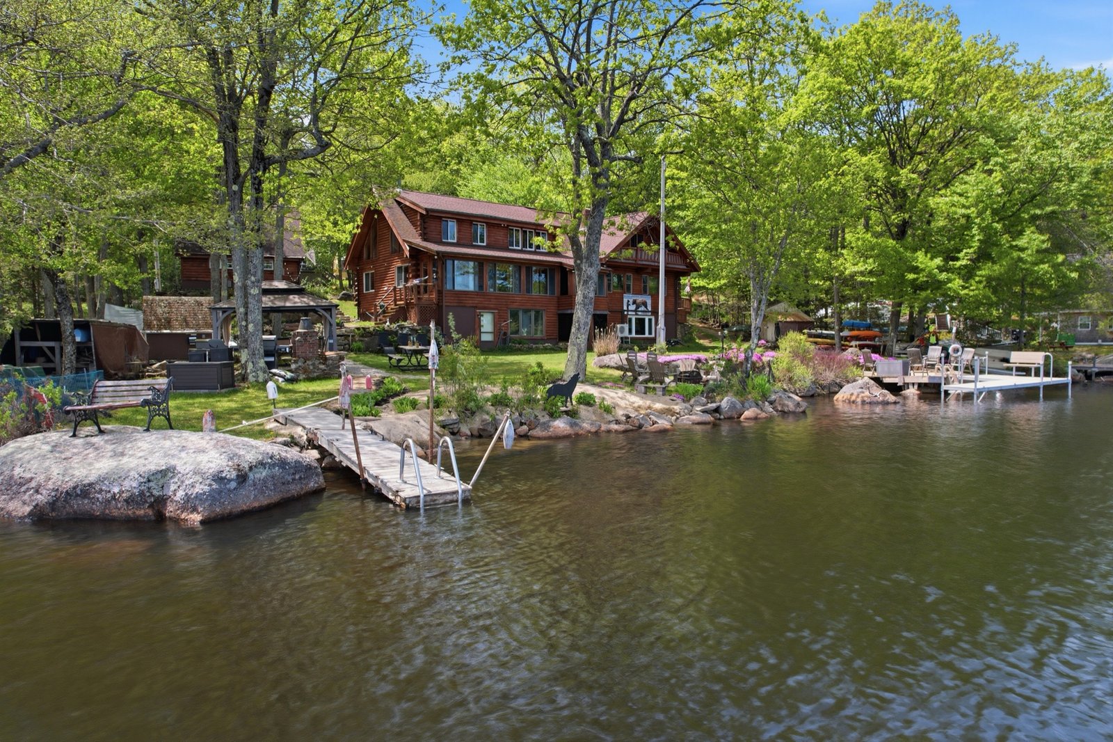 Waterfront log home seen from the lake, with dock and shoreline gardens